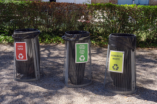 three garbage baskets, one for general waste, the other two for recyclables, in a park in Venice, Italy