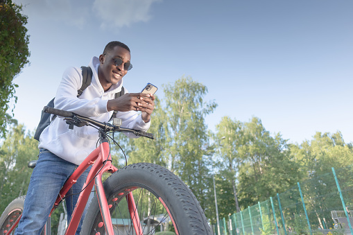 A smiling happy man with a phone in his hands and a bicycle. Sports and recreation.