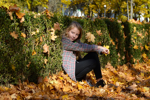Happy girl on an autumn walk. the child walks in the park and enjoys the beautiful autumn nature and the warm rays of the sun. the concept of active lifestyle and outdoor walks