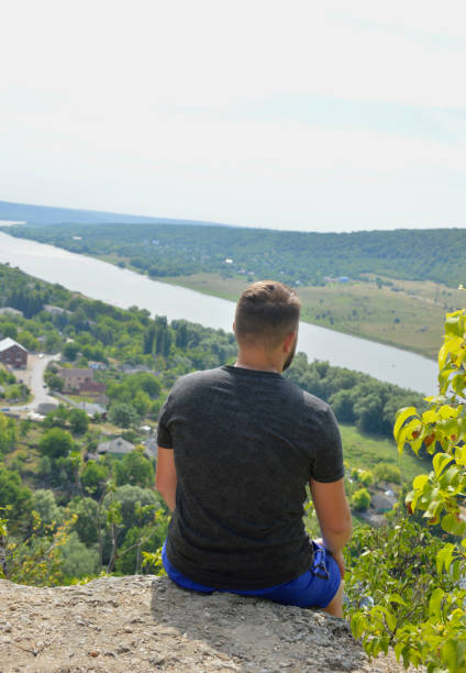 istock young man sitting on the edge of a cliff after climbing 1431099586