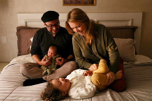 Young Happy Family with newborn baby sitting on the bed playing at home