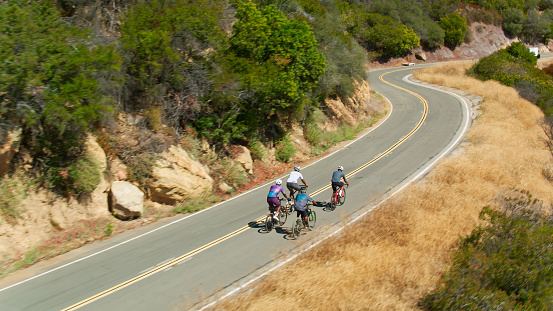 Drone shot of a group of middle-aged African-American men wearing lycra cycling clothes enjoying a morning ride on a sunny day in the Santa Monica Mountains in Malibu, California.