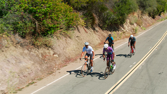 Drone shot of a group of middle-aged African-American men wearing lycra cycling clothes enjoying a morning ride on a sunny day in the Santa Monica Mountains in Malibu, California.