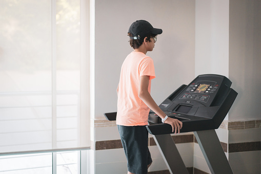 Caucasian teen boy runs on treadmill. Sports and healthy lifestyle