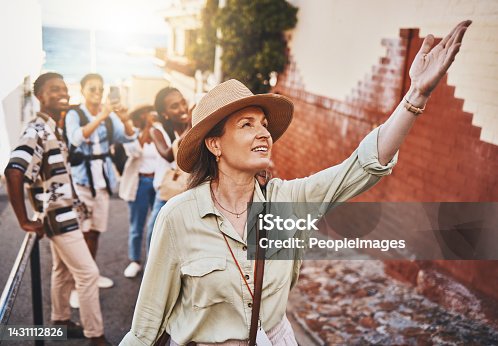istock Travel, education and a teacher with students on school field trip, on urban tour. Woman, city guide and group of happy tourists, pointing at local architecture and learning on international holiday. 1431112826
