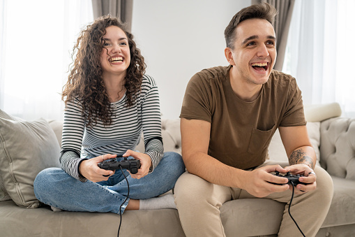 Two people couple man and woman boyfriend and girlfriend husband and wife or friends play console video games hold joystick controller happy smile emotional gesture reaction family leisure copy space