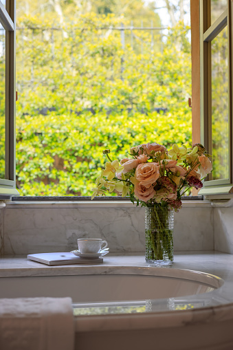 Coffee and book by the bath tub and window