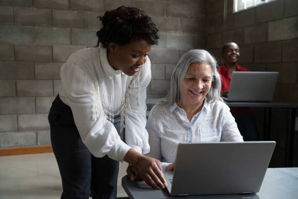 istock Young female computing teacher answering the question from a female student at a technology course for seniors 1431116714