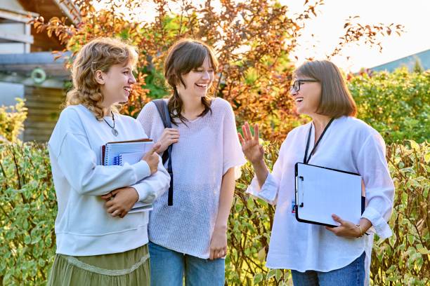 Female teacher talking to teenage female students outdoor stock photo