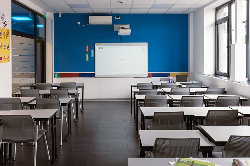 Empty classroom with desks, chairs and chalkboard