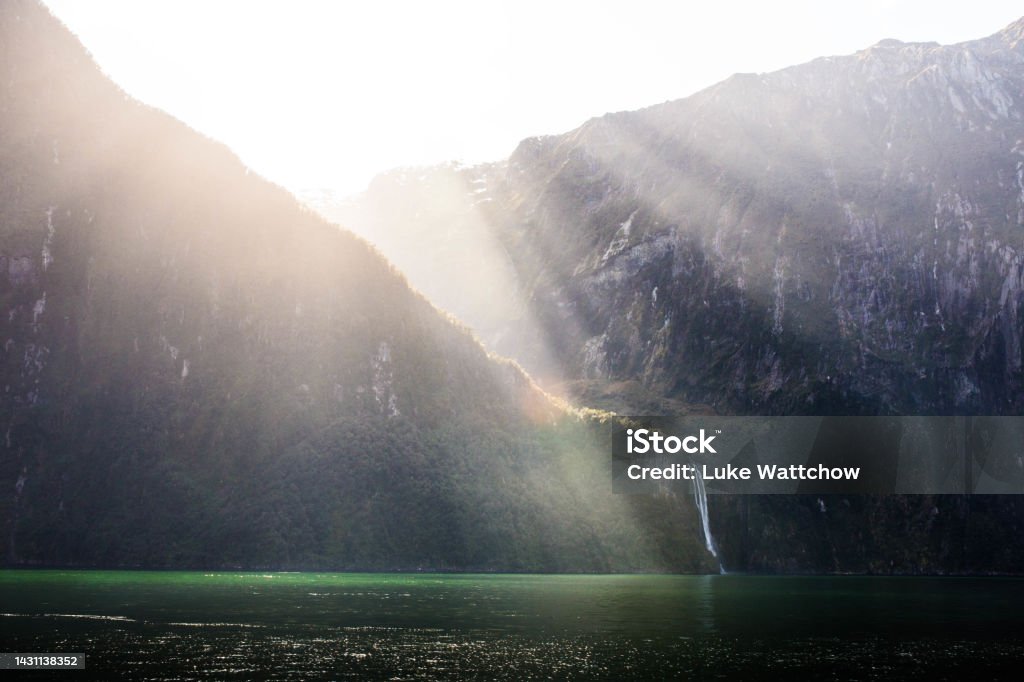 Sunrays over Milford Sounds Sunrays falling over a waterfall in Milford Sounds Milford Track Stock Photo