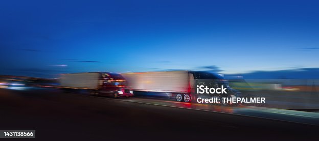 istock Two semi-truck sdriving on the highway at night - motion blur 1431138566