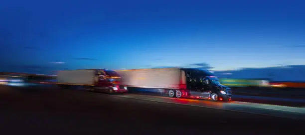 Photo of Two semi-truck sdriving on the highway at night - motion blur
