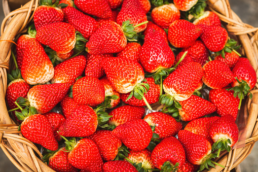 Close-up fresh ripe organic strawberry in wooden wicker basket. Top view
