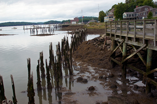Wiscasset  Maine pier on overcast day in summer showing old houses, boats, rotting timber and ocean