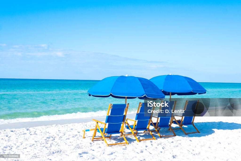 Beach Chairs and Umbrella A group of blue beach chairs with umbrellas sitting on white sandy beaches in front of the ocean. Florida - US State Stock Photo