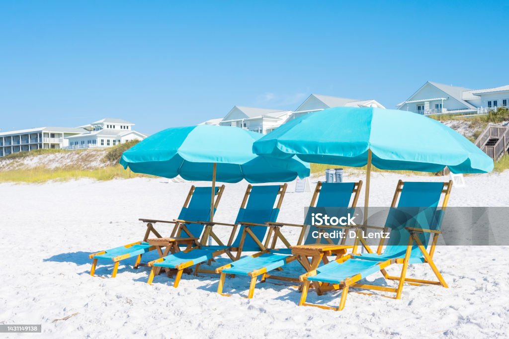 Beach Chairs and Umbrella A group of blue beach chairs with umbrellas sitting on white sandy beaches in front of the ocean. Armchair Stock Photo