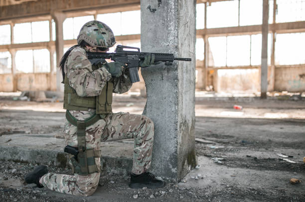 istock Female soldier kneeling while aiming a rifle at a target 1431164144
