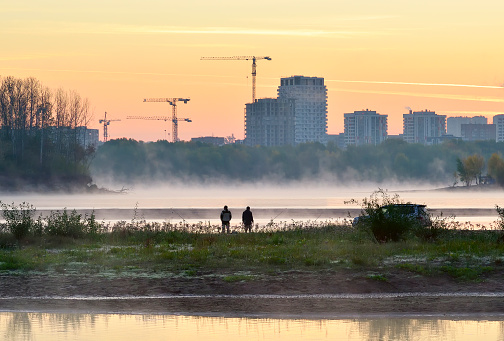 Novosibirsk, Siberia, Russia, 09.03.2022. Dawn on the banks of the Ob. The new residential area of Beregovaya by the river in the morning fog.