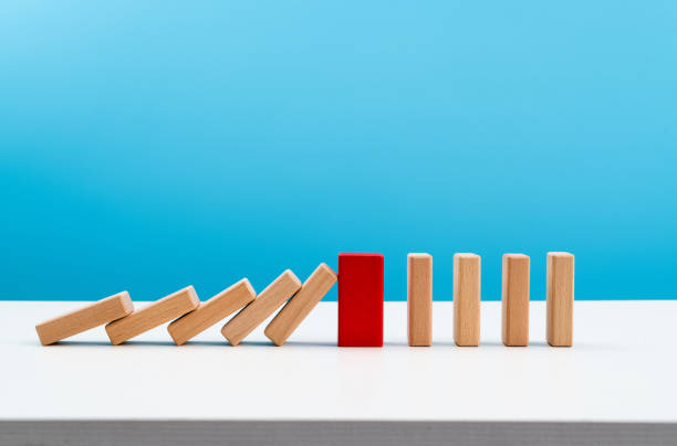 Red wooden block stop other falling dominos stock photo