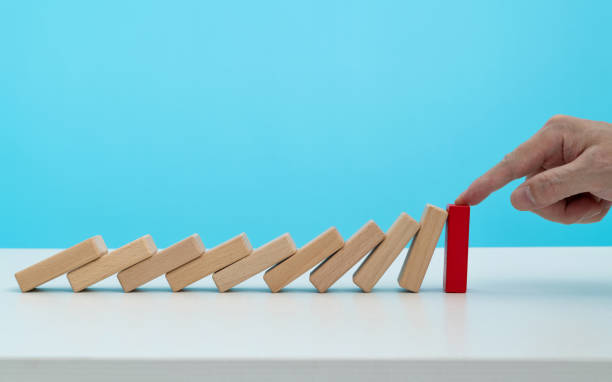 istock Man hand stopping the dominos falling 1431187930