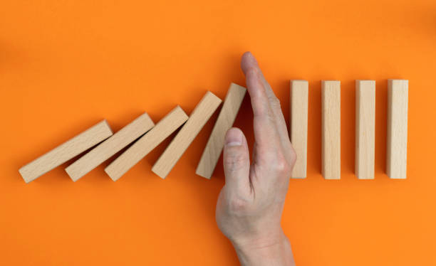 istock Man hand stopping the dominos falling 1431187969
