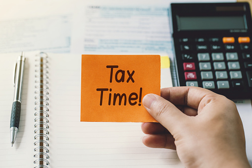 Time for Taxes Money Financial Accounting Taxation Concept.Hand holding a paper with tax time text on tax forms. Assistance with filing tax forms and calculations.Financial research.