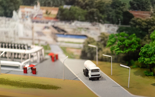 A logistic truck (model) on the road in front of oil refinery plant. Refinery and energy industrial working scene, close-up and selective on the object.