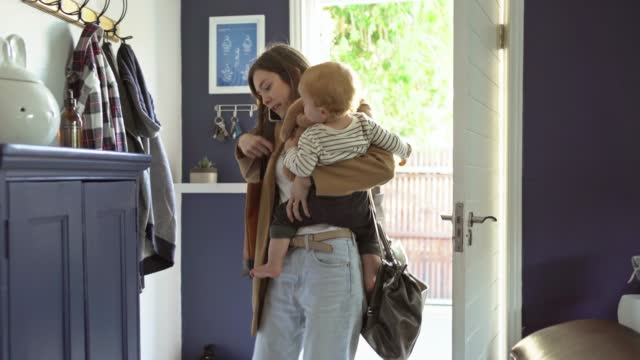Mom talking on a phone and carrying her son after arriving home from shopping