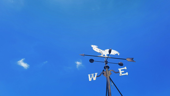 Rooster weather vane to indicate the wind direction on blue sky