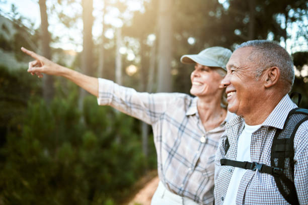 senderismo, aventura y libertad con una pareja de personas mayores disfrutando y explorando el bosque o los bosques y uniéndose. feliz, despreocupado y explorando hombres y mujeres jubilados mirando las vistas al aire libre - gente de tercera edad activa fotografías e imágenes de stock