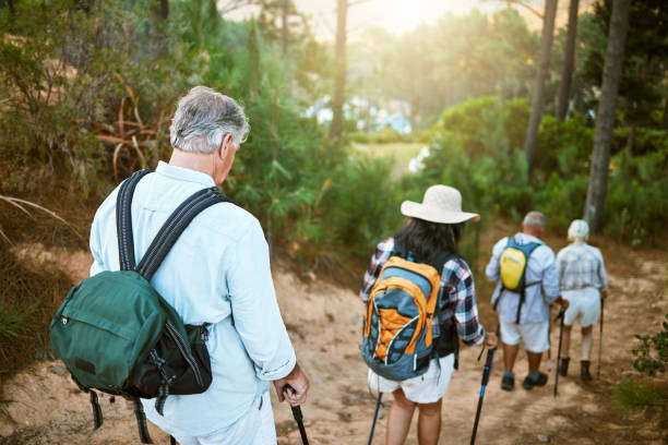 Hiking, adventure and exploring with a group of senior friends walking on a trail in the forest or woods. Rearview of retired people taking a hike or journey on a discovery vacation outdoors senderismo, aventura y exploración con un grupo de amigos mayores que caminan por un sendero en el bosque o el bosque. vista trasera de personas jubiladas que realizan una caminata o un viaje en unas vacaciones de descubrimiento al aire libre