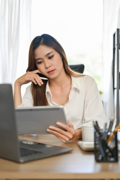 istock Attractive Asian businesswoman working at her office desk, using digital tablet 1431223299