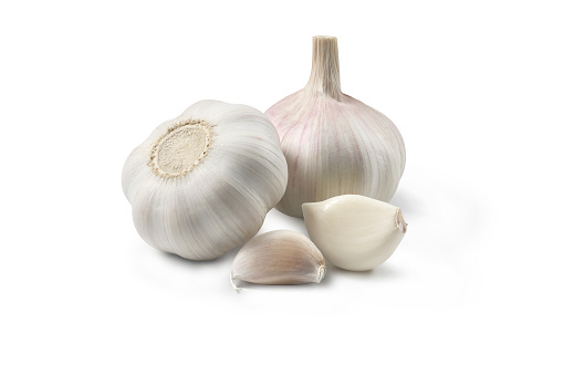 Two heads of garlic with cloves of garlic placed on a white