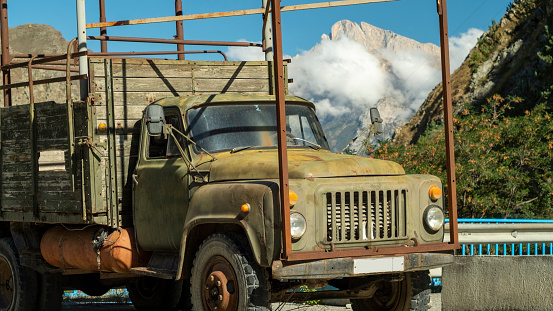 An old military truck on a mountain road in a sunlight