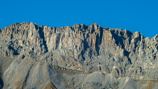 Gray mountain cliff against the sky in a sunlight from the low angle of view with a copy space for a travel related designs