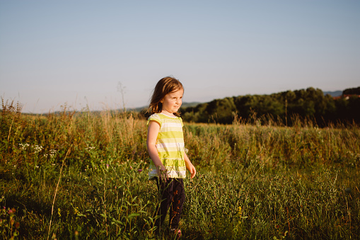 Full length of cute girl standing in the meadow during sunny day