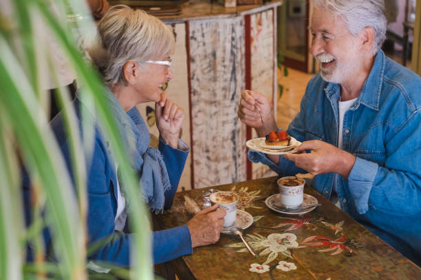 istock Lovely amused senior couple inside a coffee shop having breakfast with fruit cake and cappuccino. Two elderly people enjoying retirement and stay together 1431259036