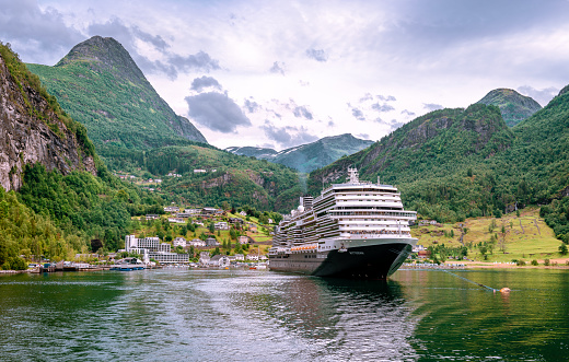 Geiranger, Norway - August 22 2022: View of the inner end of Geirangerfjord, with a cruising boat and Geiranger in the background.