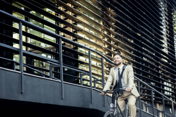 istock Businessman riding bicycle in front of modern office building. 1431267228