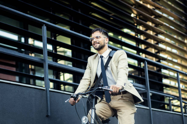 istock Businessman riding bicycle in front of modern office building. 1431267232