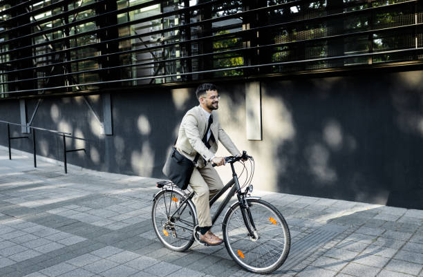 istock Businessman riding bicycle in front of modern office building. 1431267332