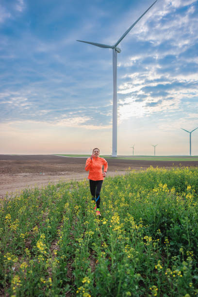 istock Young woman running through flowering plants in agricultural fields under cloudy sky 1431267962