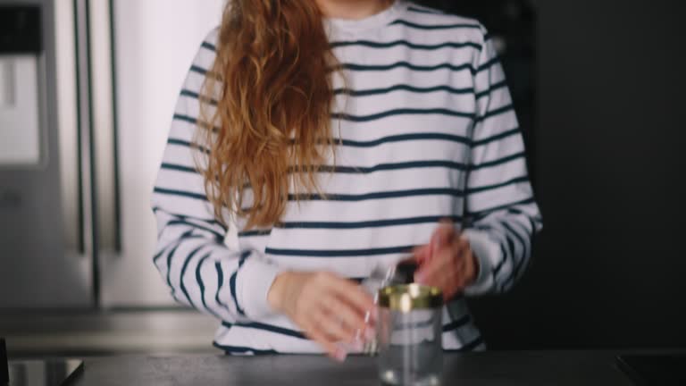 Close up footage of young woman taking pills with a glass of water at modern kitchen. Curly blonde drinks everyday vitamin drugs to be healthy. Healthcare and medicine concept.