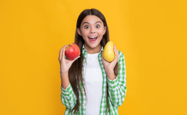 istock surprised kid with apple and pear on yellow background 1431280541