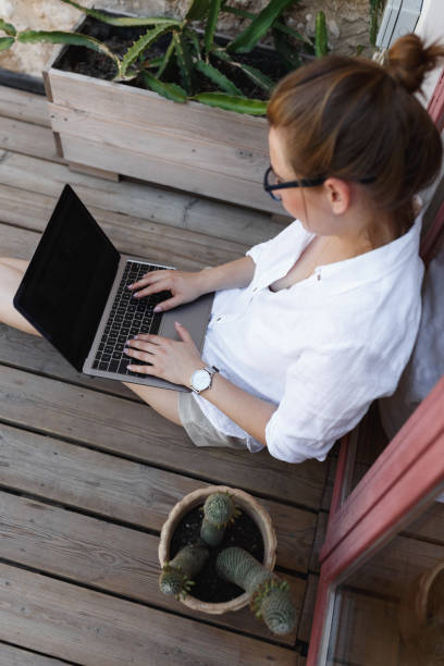 istock High angle anonymous female sitting on wooden floor with opened laptop and working or study on project at home 1431288792