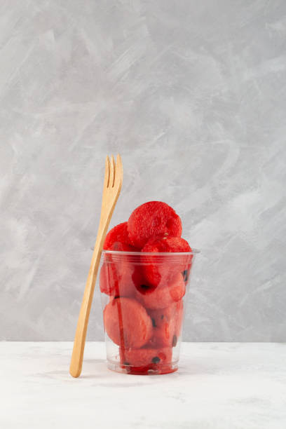istock Cut Watermelon in plastic cup on grey background. Fresh red watermelon pulp. Selective focus 1431292023