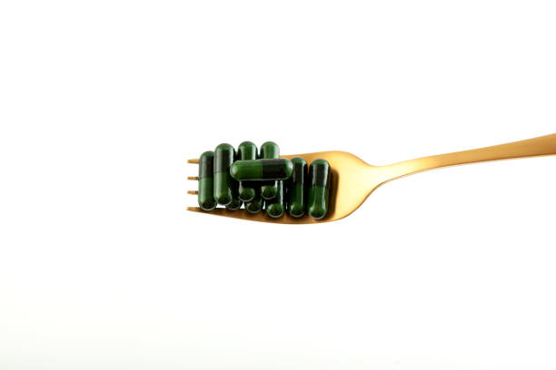 istock Antidepressants. Green capsules with plant extract on golden fork on white background. Selective focus, copy space. Nutritional Supplement. Vitamin Pill. Herbal Medicine 1431292126