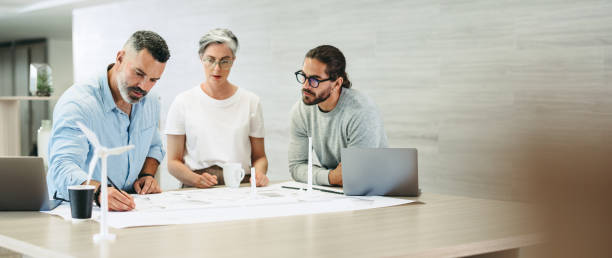istock Businesspeople working with wind turbine plans 1431295062
