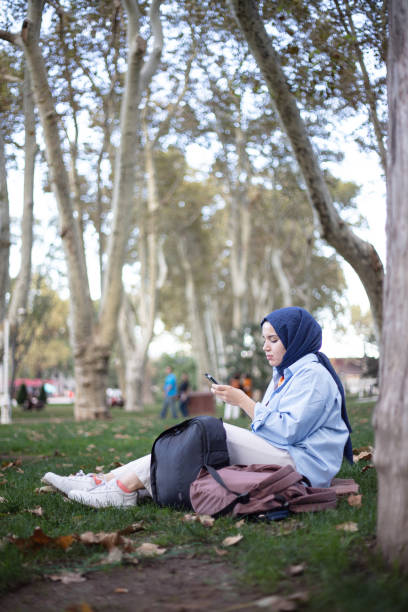 istock A young woman looking her mobile phone on the grass. 1431297529